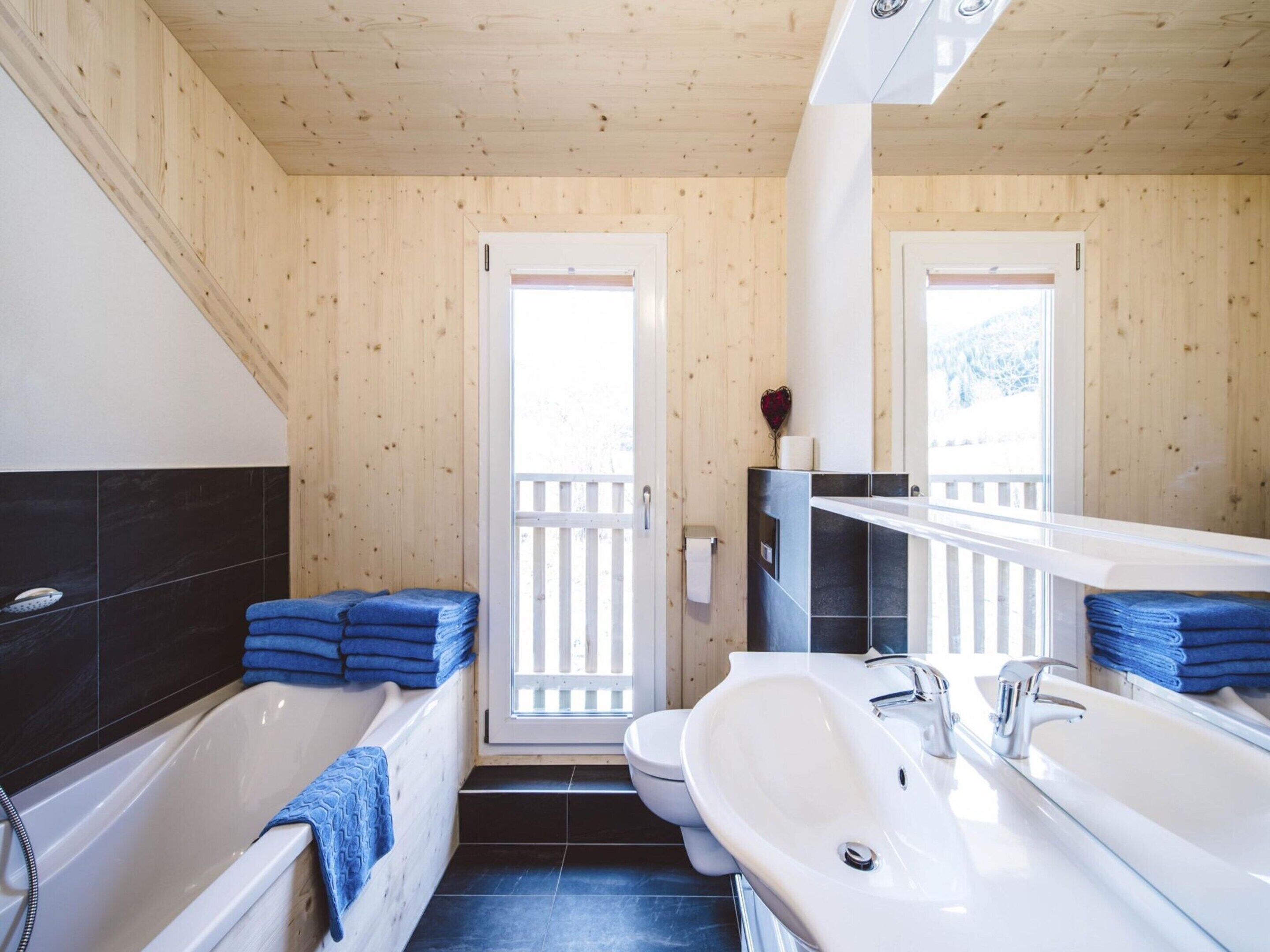A bathroom with a bathtub, a sink, and a toilet. There are blue towels stacked on the floor.