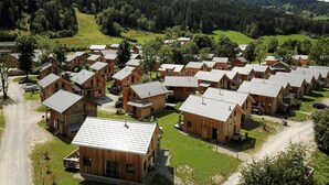 Een groep houten vakantiehuisjes met schuine daken, gerangschikt in rijen op een heuvel.