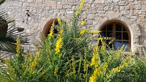 A stone building with three arched windows and a stone wall.