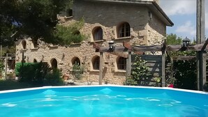 Un bâtiment en pierre doté de fenêtres en arc de cercle, avec une piscine au premier plan.