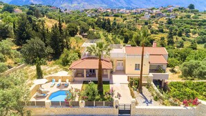 Une villa de style méditerranéen dotée d’une piscine, entourée d’une végétation luxuriante et avec des montagnes en toile de fond.