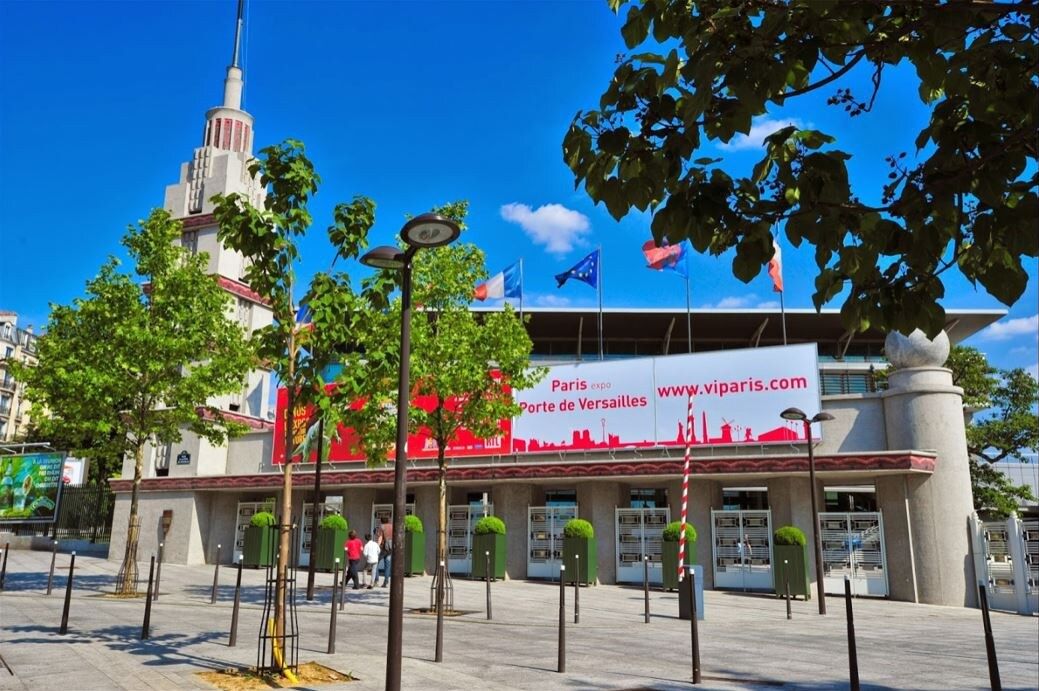 Un bâtiment sur lequel est déployée une grande banderole rouge faisant la publicité du salon Paris Expo Porte de Versailles.
