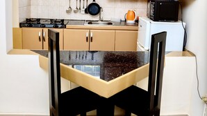 Une cuisine compacte comprenant une table à manger, des placards en bois, une cuisinière et un four à micro-ondes.