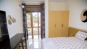 Une chambre à coucher comprenant un lit, un bureau, une armoire et donnant sur l’extérieur.