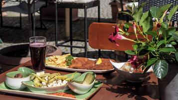 Uma mesa com diversos pratos, incluindo peixe à milanesa, batatas fritas e uma salada.