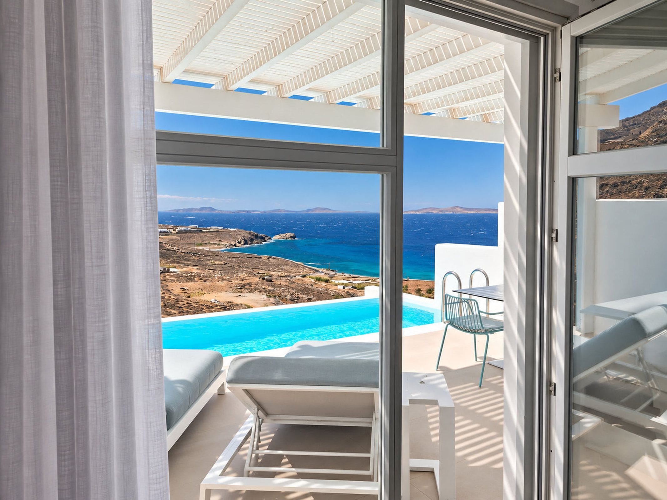 A balcony with a clear view of a swimming pool and the sea.