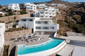 A modern resort with a pool, white buildings, and a mountainous backdrop. - Epic Blue Mykonos (Mykonos)