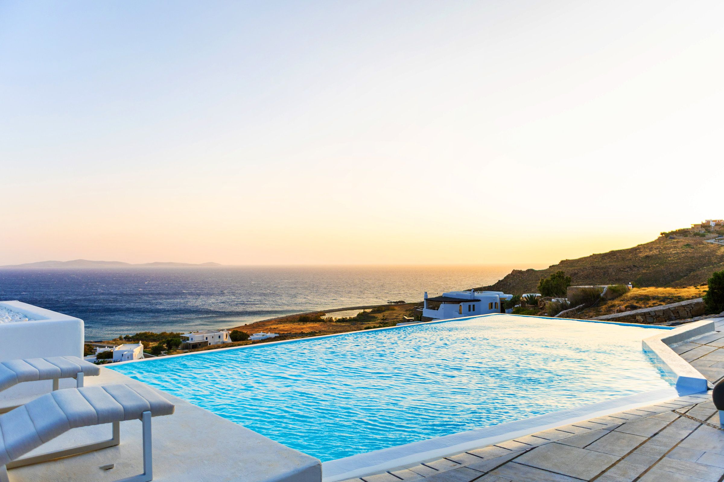 A swimming pool with a view of the sea and a hillside.