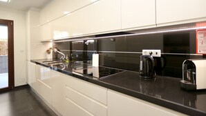 A modern kitchen with white cabinets, a black countertop, and stainless steel appliances. - Like-Home - Apt 1 bedroom, with terrace - Parque das Nações (Moscavide)