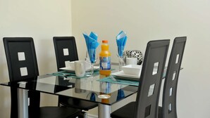 Une table à manger avec quatre chaises, un plateau en verre et une bouteille de jus d’orange.