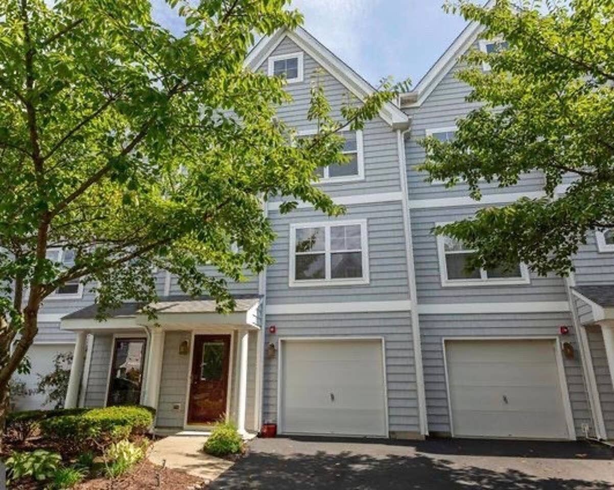 A two-story residential building with a garage and a front porch.