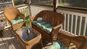 A covered outdoor deck with wicker furniture and a glass-top table. - 4BR 3.5BA POOL - Walk or bike to town and beach! (Rehoboth Beach)