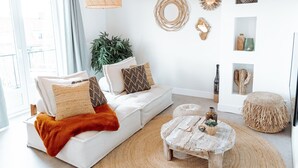 Una sala de estar moderna con un sofá blanco, una mesa de centro y una lámpara colgante.