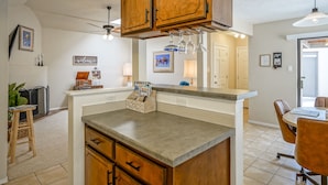 A kitchen with wooden cabinets, a countertop, and a dining area with a table and chairs. - Retro Condo in the North East Heights, 2bd/1ba, garage, Pet friendly (Albuquerque)