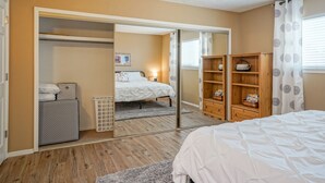 A bedroom with a bed, a wardrobe, a mirror, and a small wooden shelf with books. - Retro Condo in the North East Heights, 2bd/1ba, garage, Pet friendly (Albuquerque)