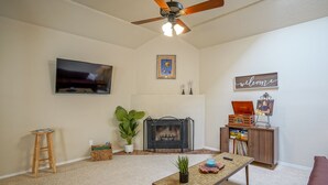 A living room with a fireplace, television, and a ceiling fan. - Retro Condo in the North East Heights, 2bd/1ba, garage, Pet friendly (Albuquerque)
