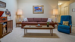 A living room with a brown sofa, a blue armchair, a coffee table, and two lamps. - Retro Condo in the North East Heights, 2bd/1ba, garage, Pet friendly (Albuquerque)