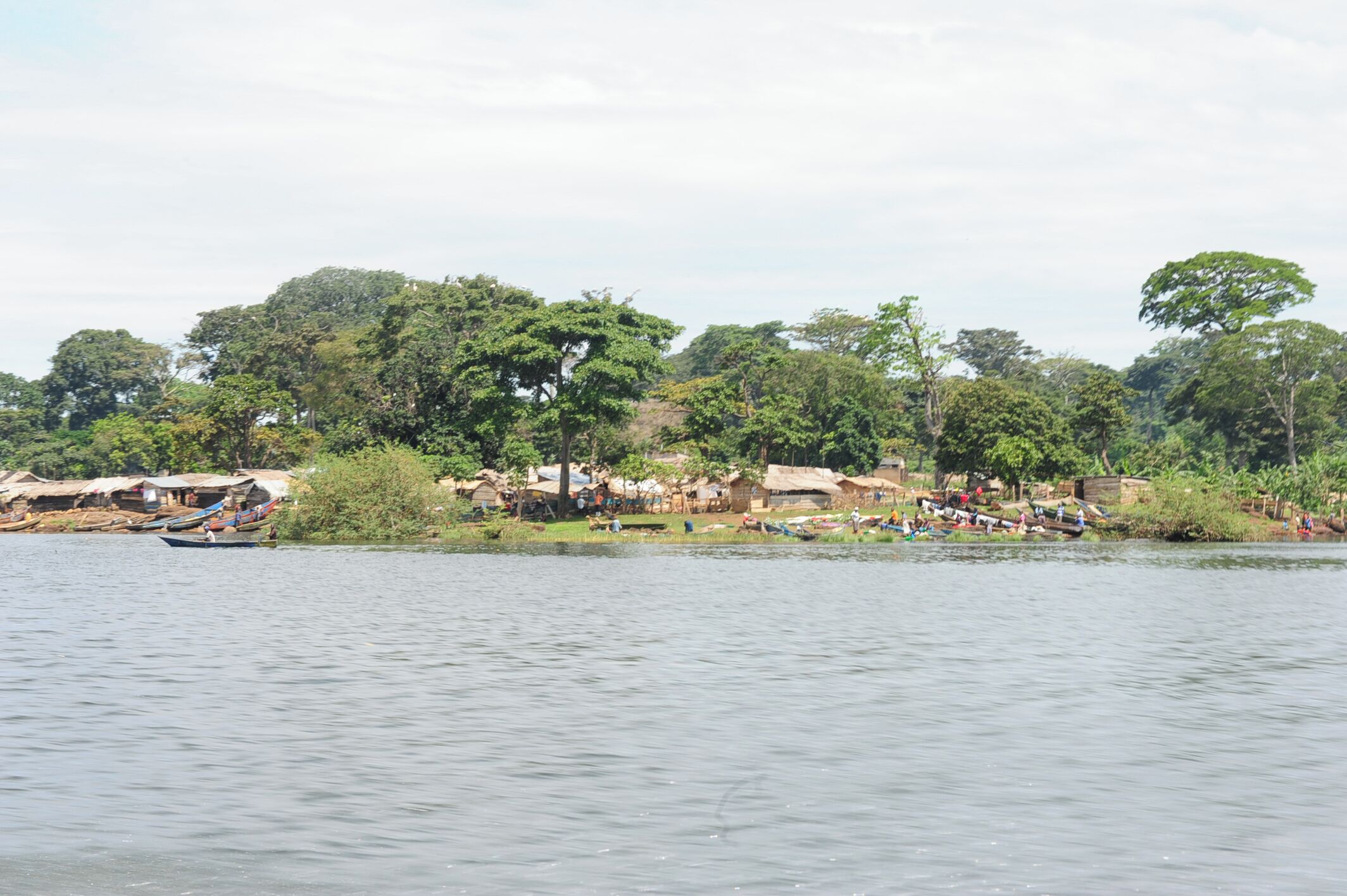 A riverside village with thatched-roof houses and boats on the water.