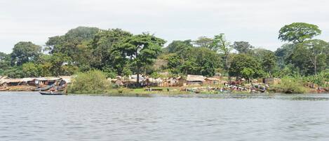 A riverside village with thatched-roof houses and boats on the water.