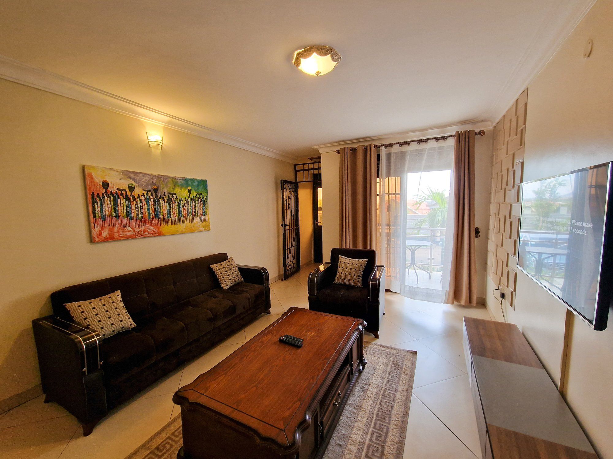 Una sala de estar con un sofá, sillones, una mesa de centro, un cuadro y un televisor.