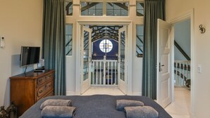 A bedroom with a bed, a dresser, a TV, and a view of a balcony through a glass door. - Church conversion for a unique stay and experience: 5 bedrooms and 5 bathrooms (Rinsumageest)