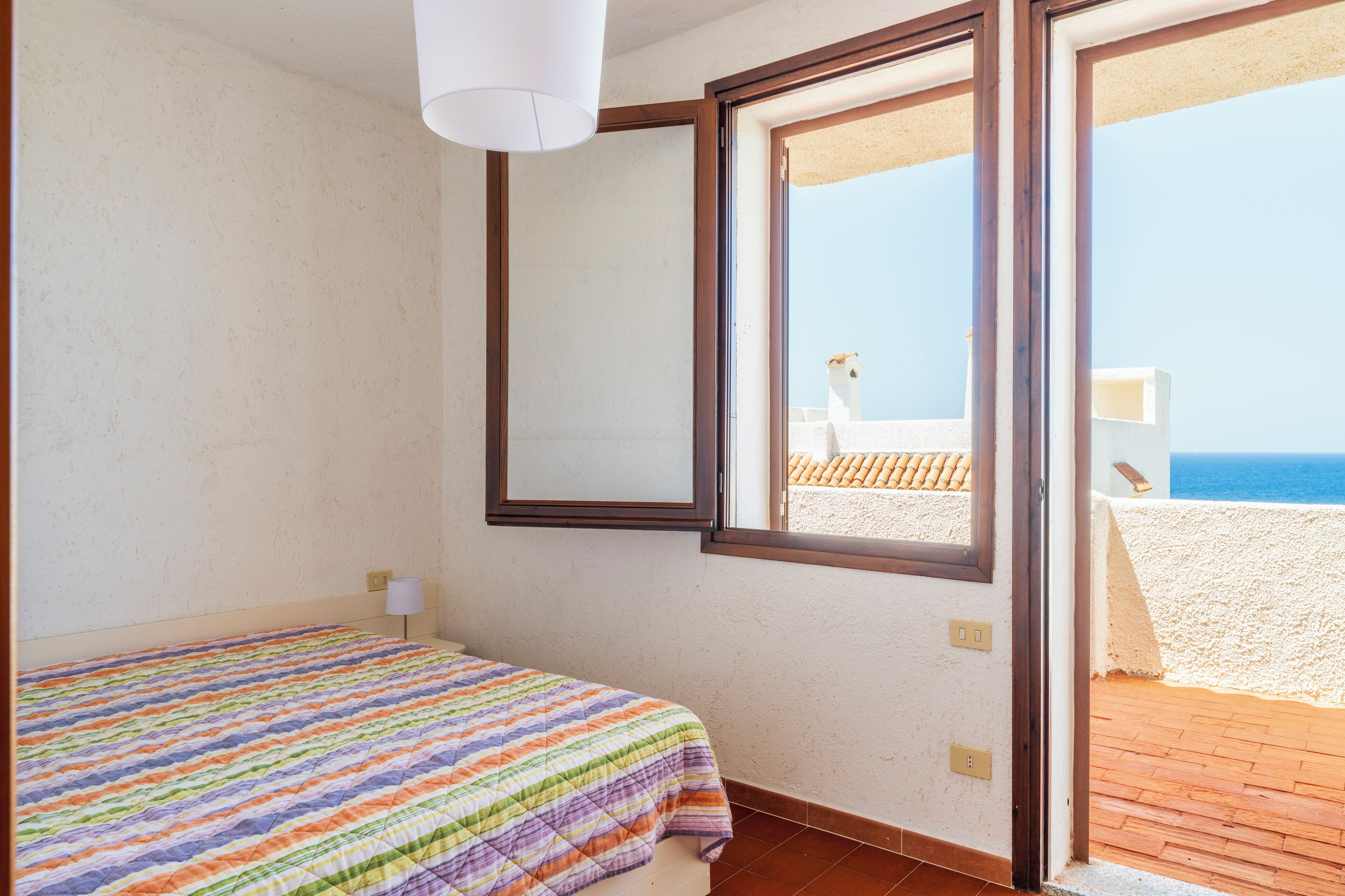 Un dormitorio con cama, ventana y vista a la playa.