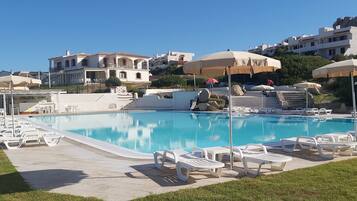 Piscina a l'aire lliure de temporada, para-sols i gandules
