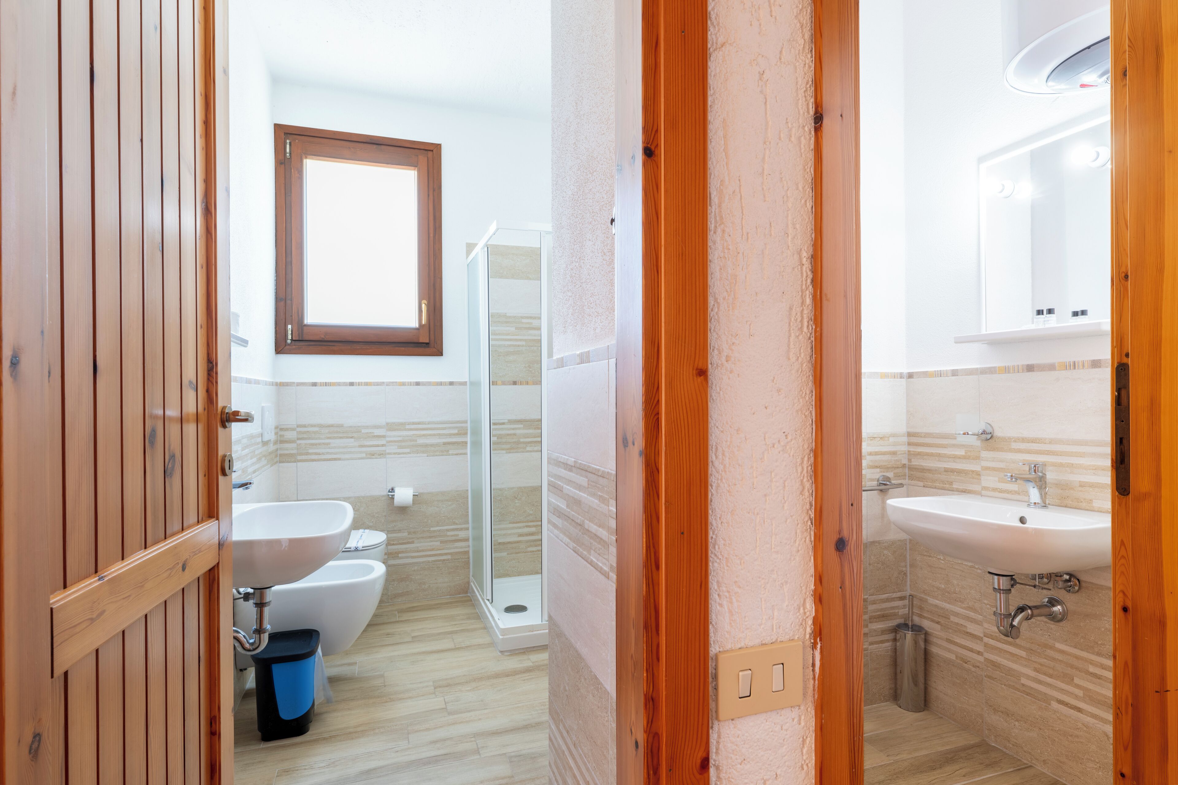 Une salle de bain avec une porte en bois, un lavabo, des toilettes et une douche.