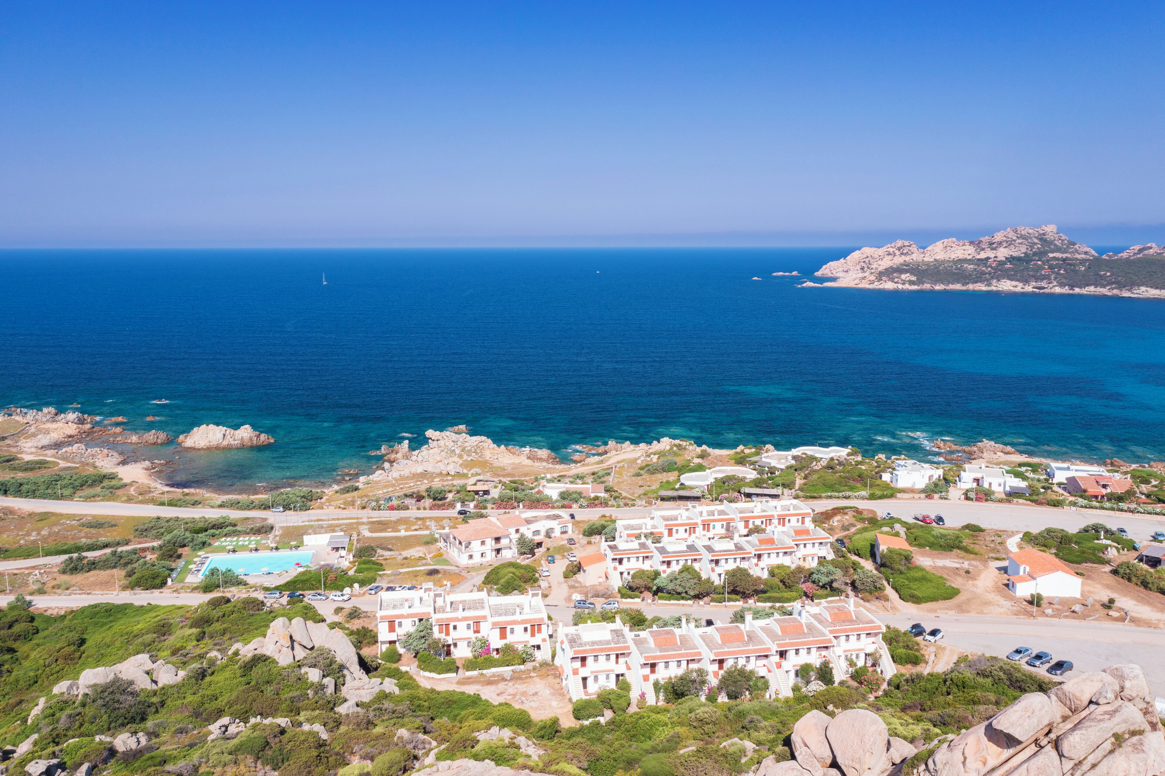 A coastal resort with villas, a swimming pool, and rocky terrain.