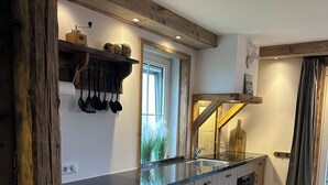 A modern kitchen with wooden beams, a large window, and a built-in oven.