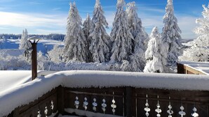 A snowy landscape with snow-covered trees and a wooden fence.