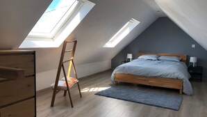 A bedroom with a sloped ceiling, skylights, a wooden bed, bedside tables, and a dresser.