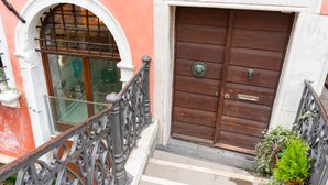 Un edificio de dos plantas con una puerta de madera marcada con el número 6077.