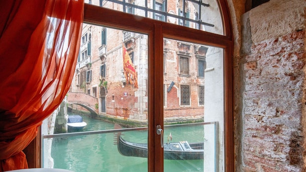 Habitación con vista a un canal y barcos, que cuenta con una puerta de madera y una cortina.