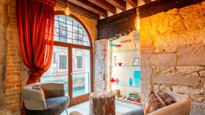 Una habitación acogedora con pared de piedra, un amplio ventanal de arco y una repisa de cristal con adornos.