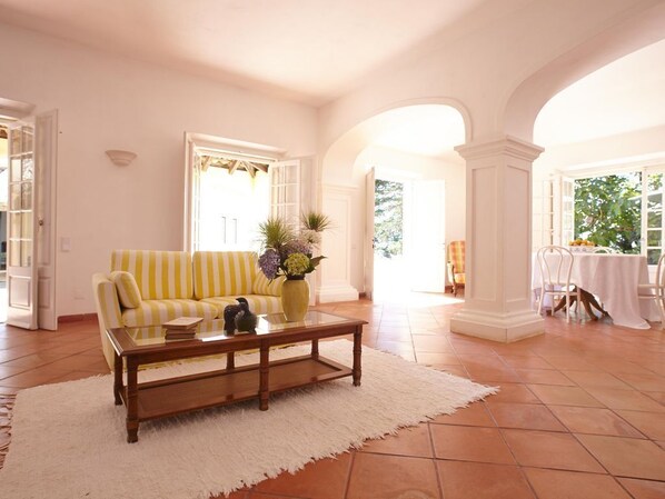 A living room with a yellow-striped sofa, a wooden coffee table, and a white rug.