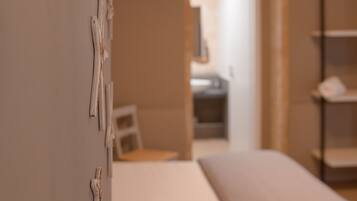 A bedroom with a bed, a wall-mounted shelf, and a door leading to another room.