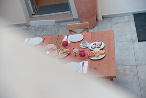 Una mesa de madera dispuesta para una comida, con platos, cubiertos y diversos alimentos.