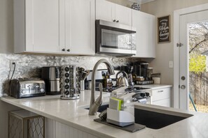 Cocina moderna con armarios blancos, electrodomésticos de acero inoxidable y salpicadero negro.