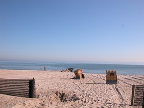 Ein Strand mit einer Holzlattenzaun, einem Rettungsturm und freiem Blick auf den Ozean.
