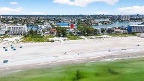 A coastal cityscape with a beach, buildings, and a marina.