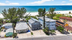 A coastal residential area with houses, a beach, and a clear sky.