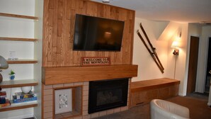 A living room with a wooden wall, a flat-screen TV, a fireplace, and a ski rack. - Shuttle Bus. Picturesque. King Bed. Updated. Parking (Keystone)