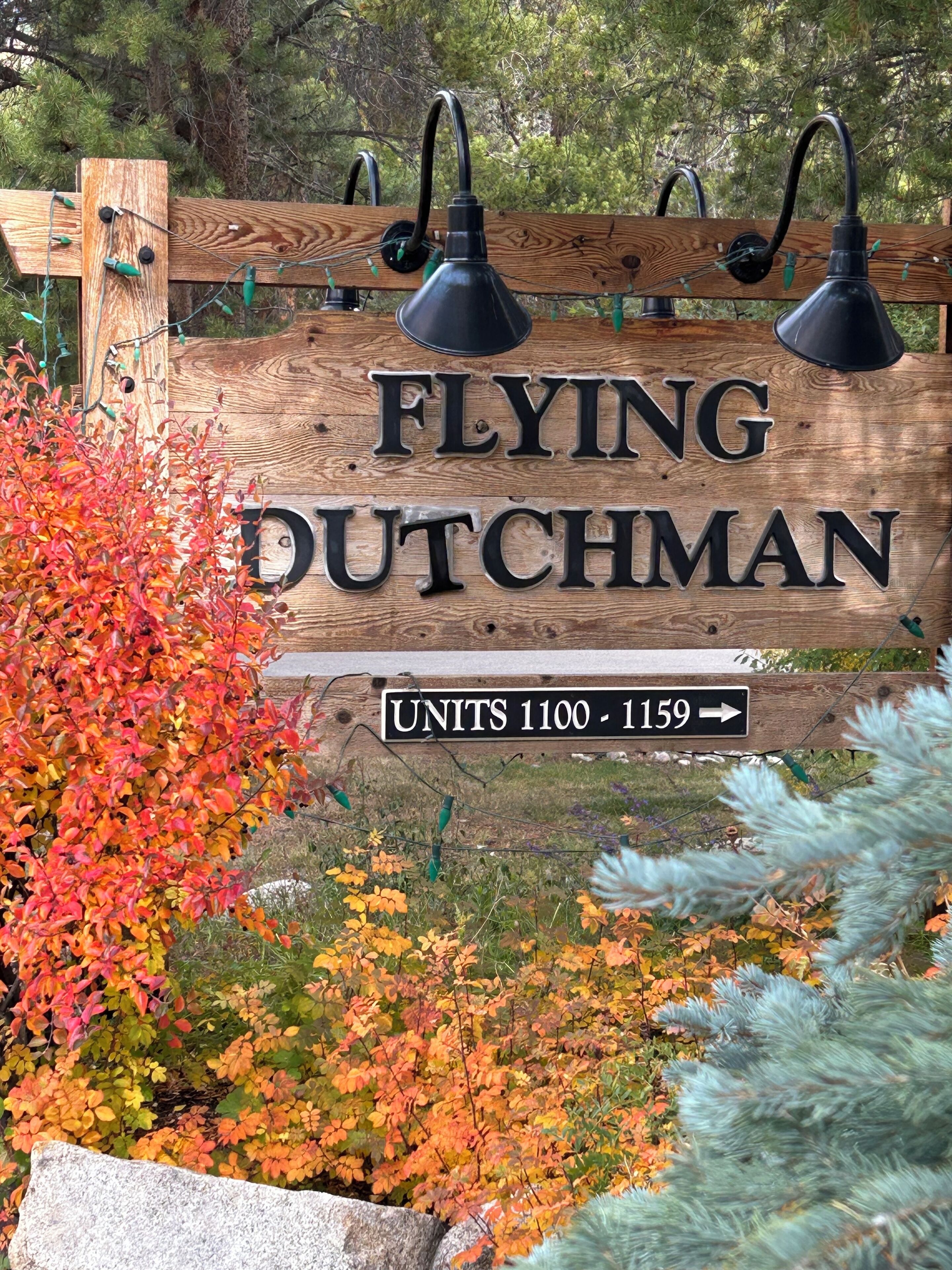 A wooden sign with 'FLYING DUTCHMAN' and directional arrows for units 1100-1159.