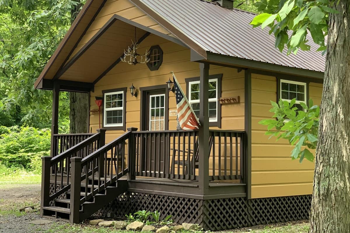 A small lodge with a porch, a staircase, and a flag.