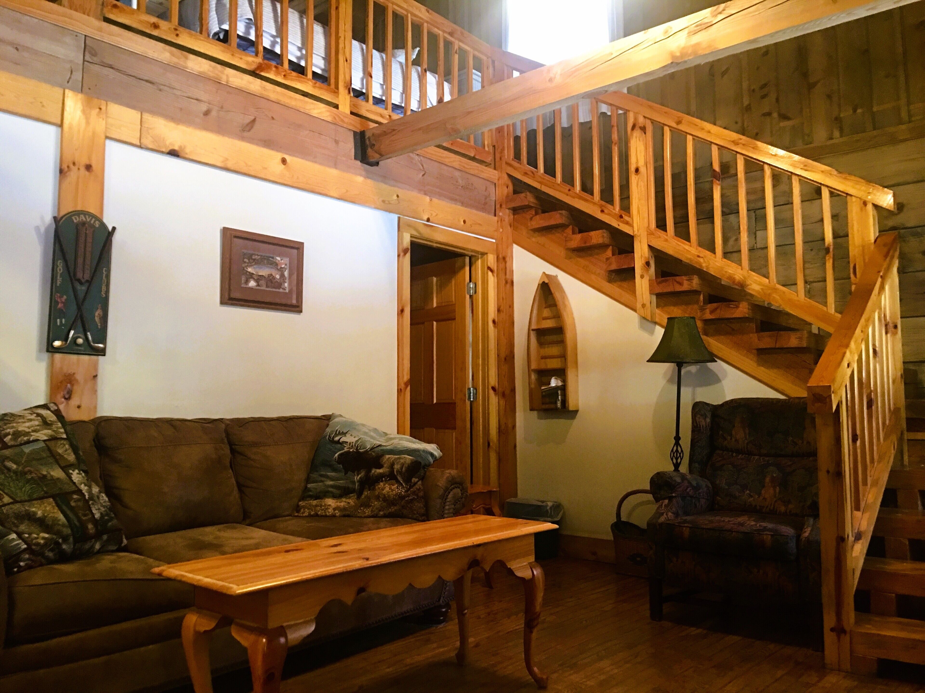 A cozy living room with a wooden staircase, a couch, a table, and a chair.