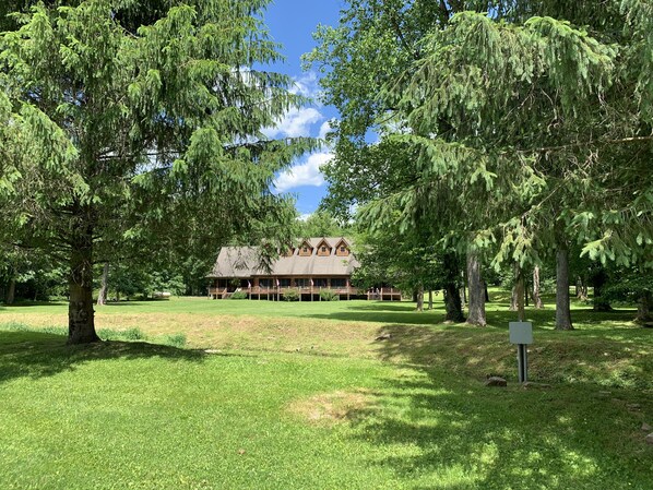 A lodge with a large porch and a covered deck, surrounded by lush green trees and grass. - Elk Springs Resort (Monterville)
