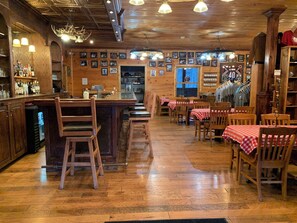 A rustic bar area with wooden furniture, a counter, and a variety of bottles. - Elk Springs Resort (Monterville)