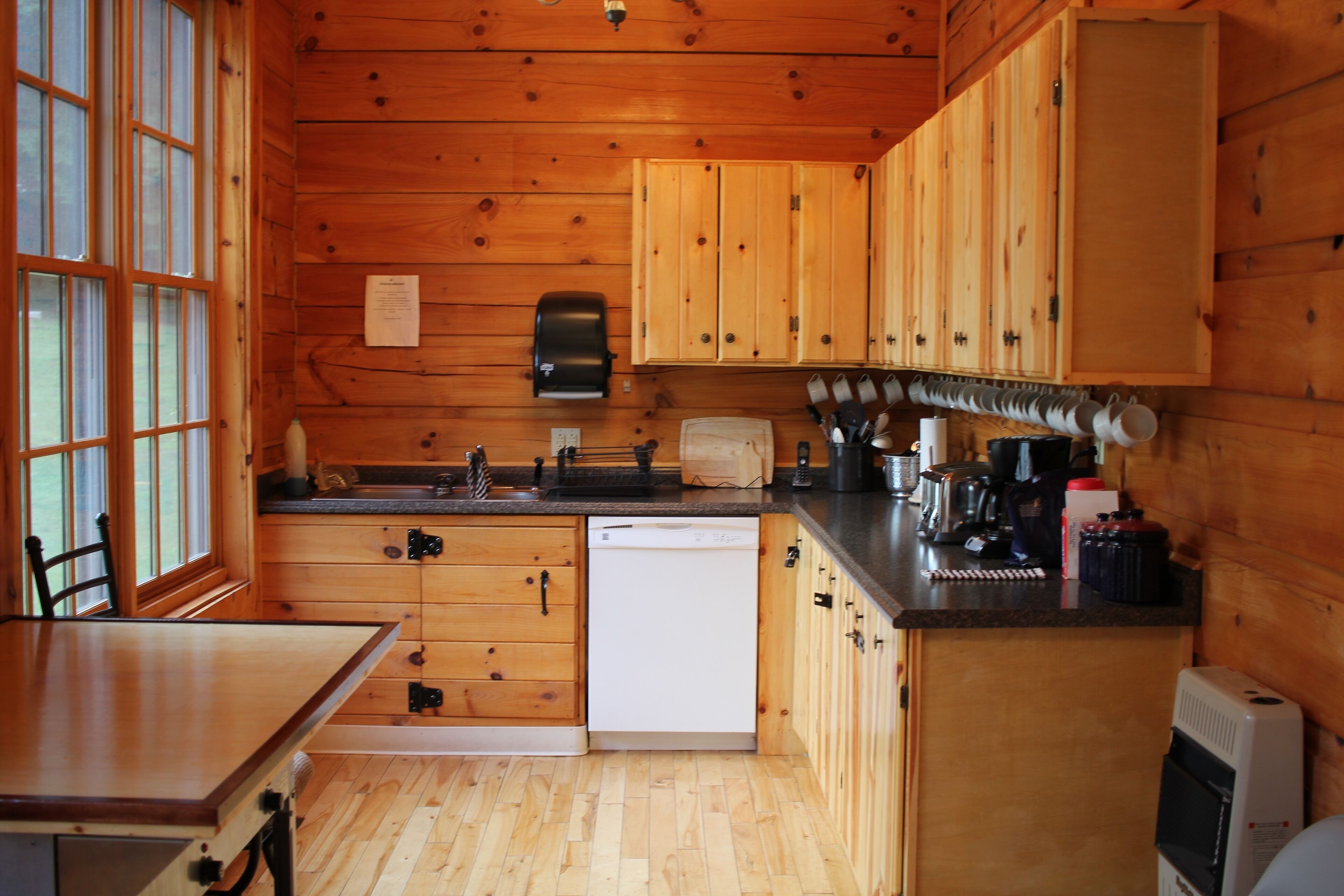 A wooden cabin kitchen with a dishwasher, wooden cabinets, a sink, and a coffee maker.