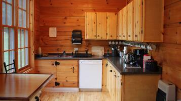A wooden cabin kitchen with a dishwasher, wooden cabinets, a sink, and a coffee maker.